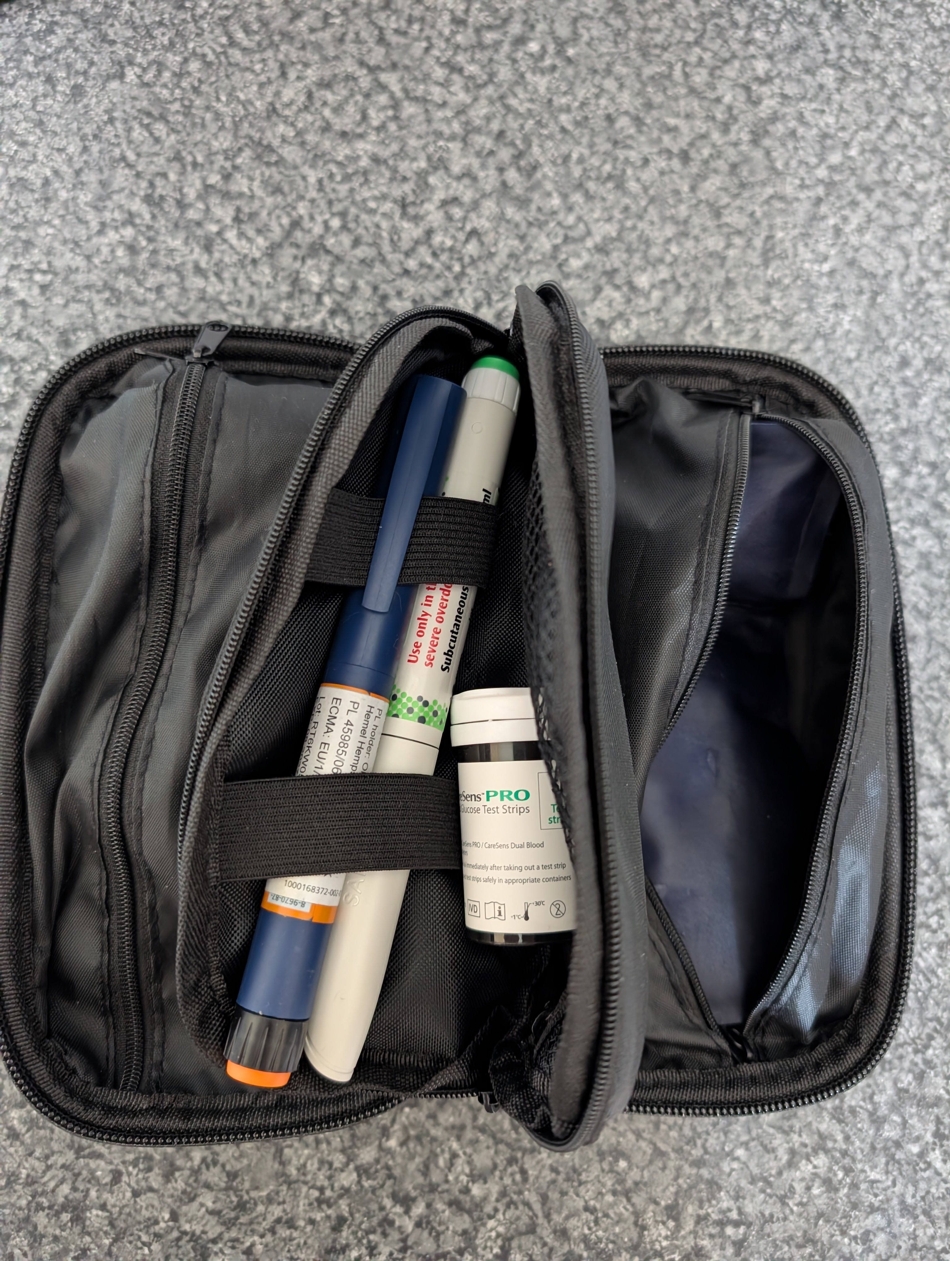 An open insulated insulin cooling wallet holding an insulin pen, a lancing device, a vial of CareSens PRO glucose test strips and a refreezable gel cooling pack